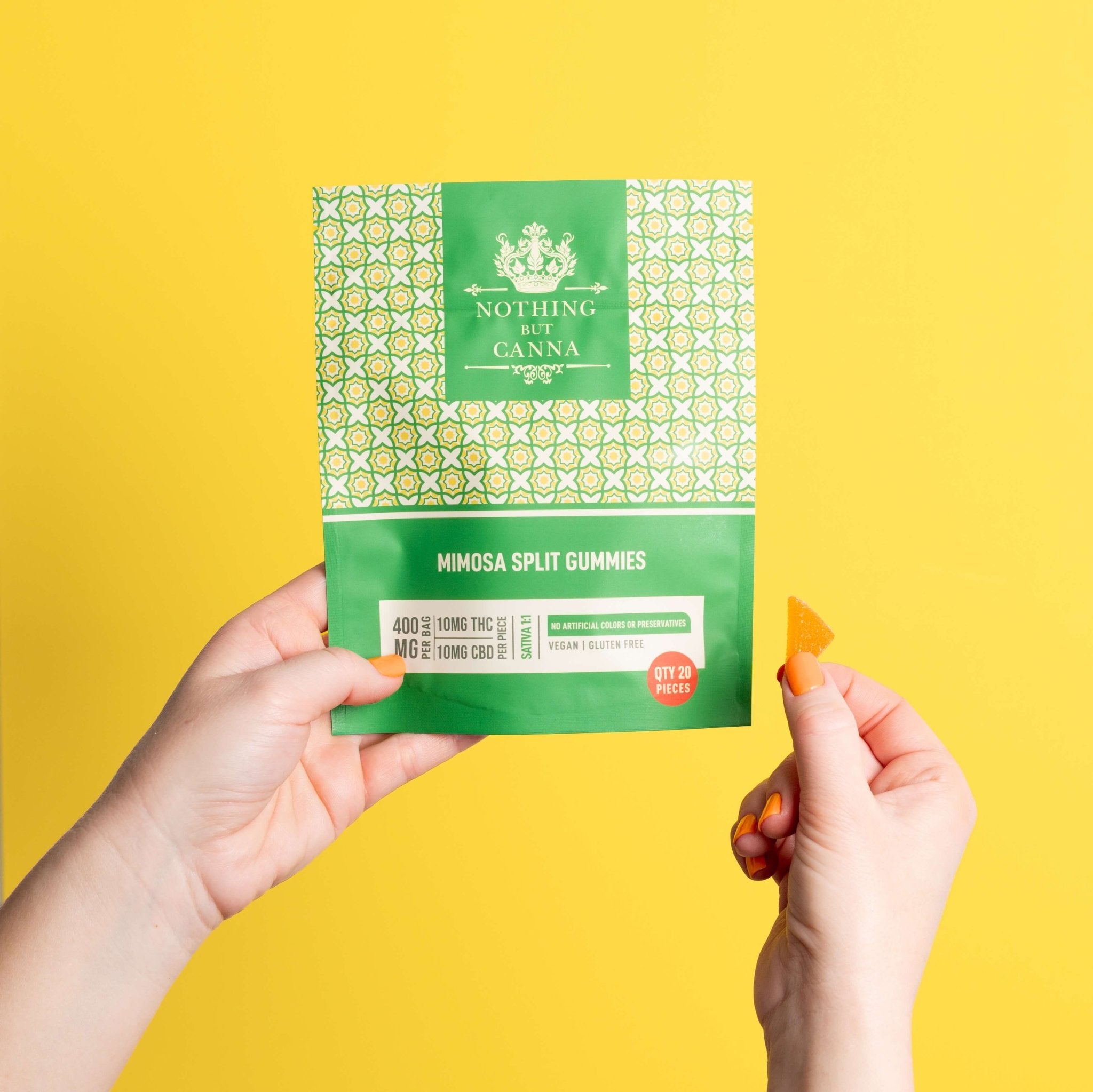 Nothing But Hemp Mimosa hemp-derived THC and CBD sativa gummies package held in one hand while the other hand displays a split half serving gummy against a yellow background in a clean lifestyle product scene
