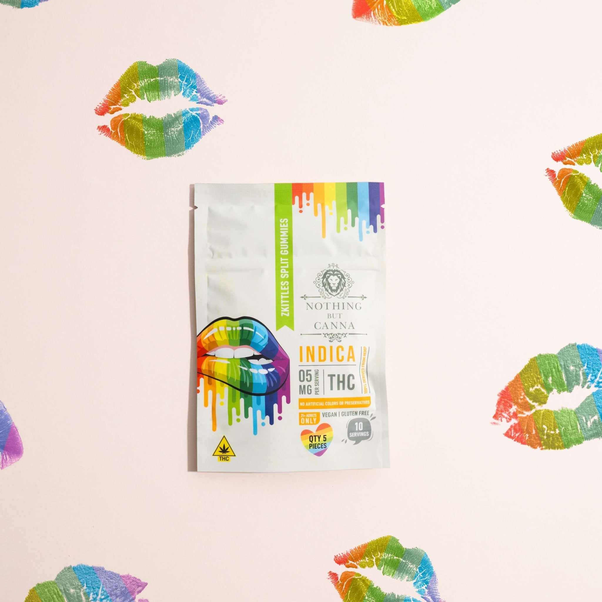 Nothing But Hemp Zkittles hemp-derived THC indica gummies package photographed on a pale gray pink background surrounded by rainbow lip print marks in a stylized lifestyle composition