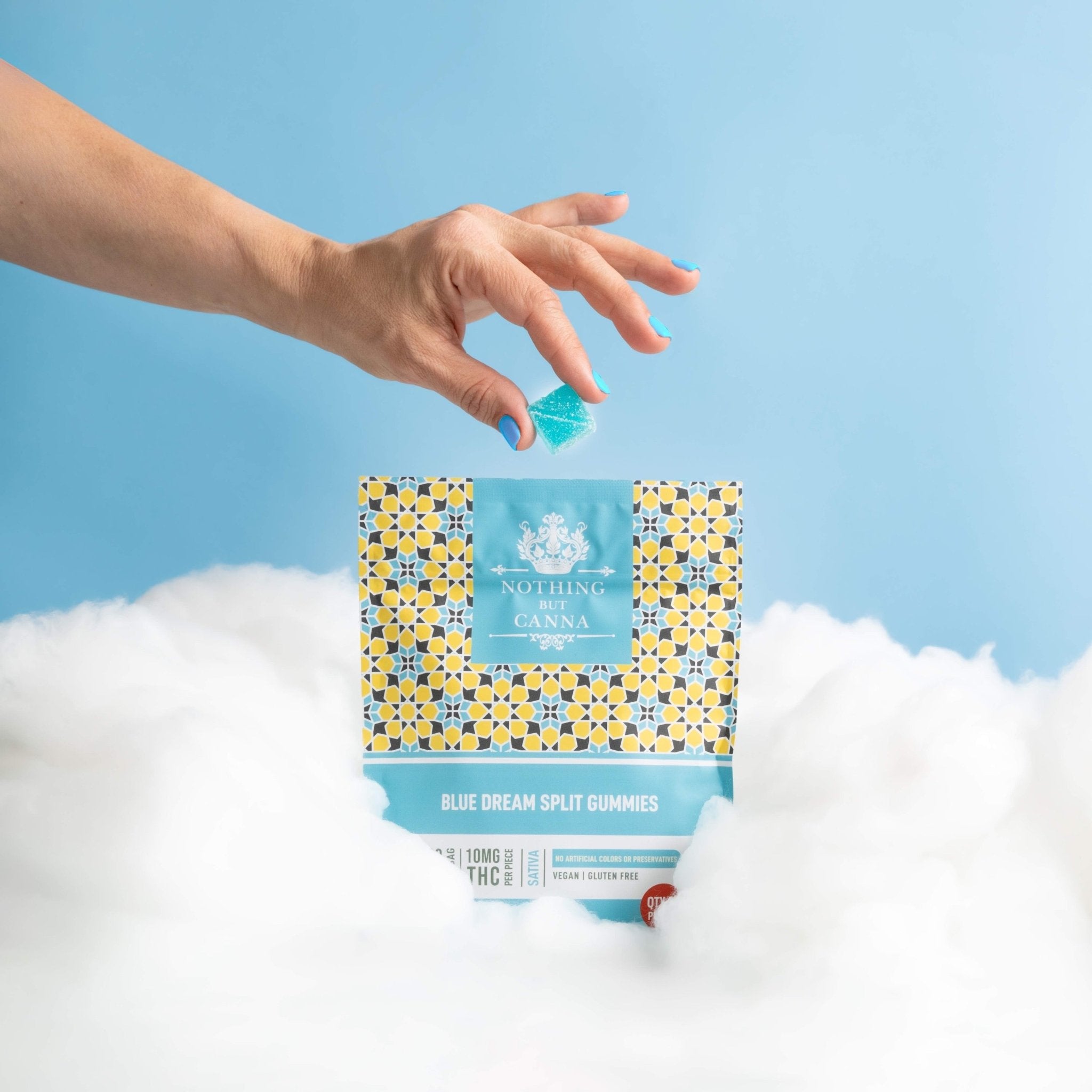 Nothing But Hemp Blue Dream hemp-derived delta-9 THC sativa gummies bag sitting in clouds against a sky blue background with a hand reaching in holding a gummy above the product